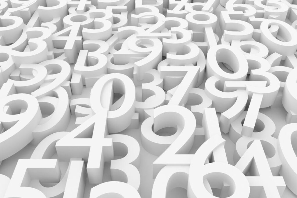 The image shows a dense arrangement of large, three-dimensional white numbers layered closely together, filling the entire frame. Digits from zero through nine overlap and stack at different angles, creating a sense of depth and repetition. The numbers appear smooth and matte, with soft shadows falling between them, suggesting a studio-lit environment. There is no visible background, as the numbers extend edge to edge, giving the impression of abundance and complexity. The uniform white color removes distraction from individual digits, encouraging focus on the overall pattern rather than specific values. The image visually represents quantity, counting, and numerical concepts, evoking ideas of mathematics, data, or early learning. The lack of color contrast emphasizes form, shape, and structure, making the scene feel modern, abstract, and slightly overwhelming, much like encountering numbers in bulk rather than in sequence.