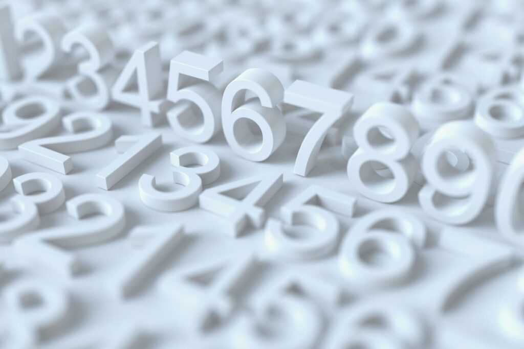 The image shows raised, three-dimensional white numbers spread across a flat surface, with only a few digits in sharp focus while the rest fade softly into the background. Numbers such as five, six, seven, and eight stand upright, casting gentle shadows that enhance their depth. The shallow depth of field draws attention to the foreground digits, while the blurred numbers behind suggest continuity and scale. The monochromatic white palette creates a clean, minimalist aesthetic, emphasizing shape and spacing rather than color. The scene feels orderly yet expansive, visually representing counting, sequencing, or numerical progression. The smooth surfaces and even lighting give the image a polished, conceptual quality, often associated with abstract representations of math, data, or education. It conveys clarity, structure, and focus within a broader numerical context.